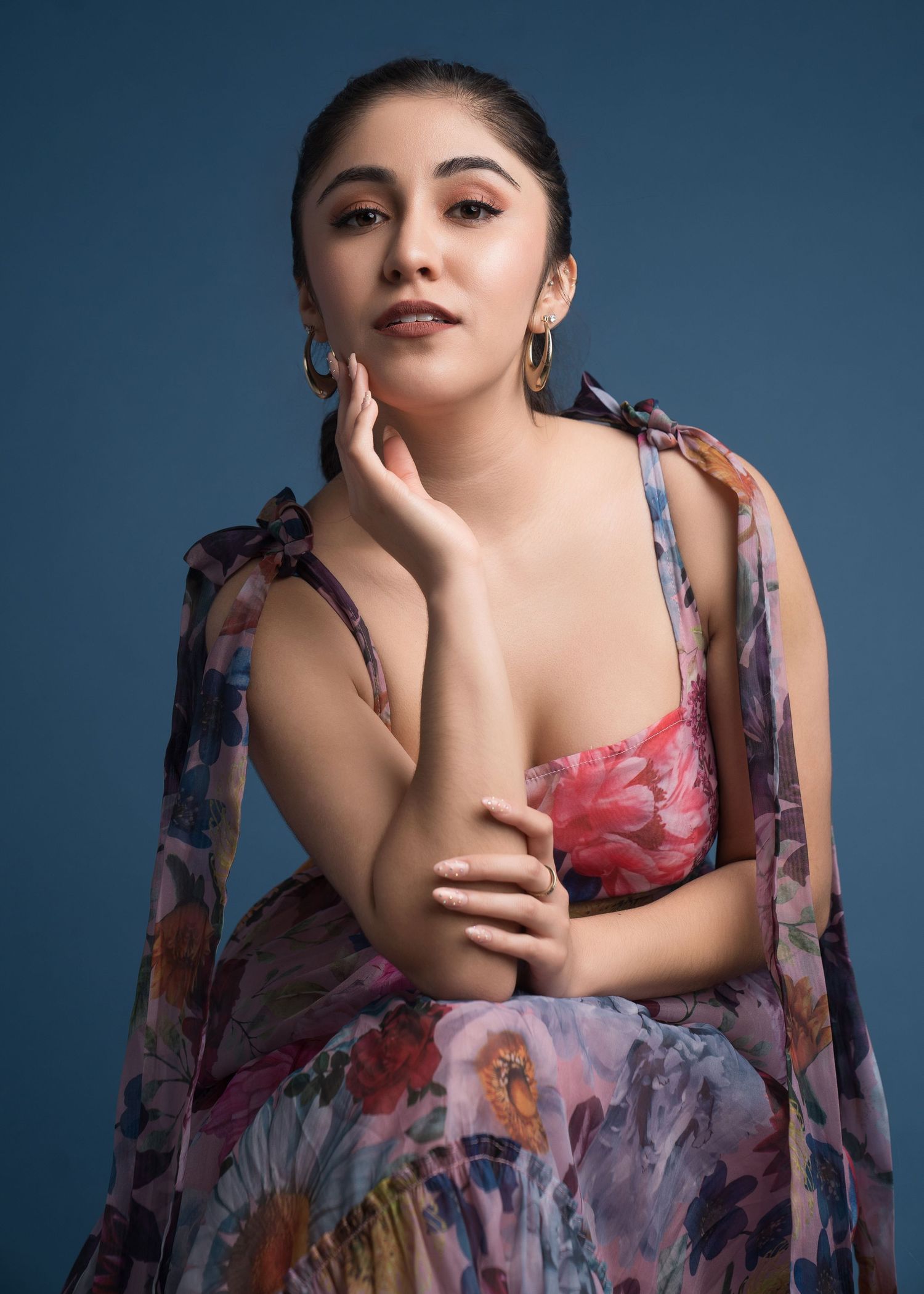 Studio portrait in floral print wrap against blue background.