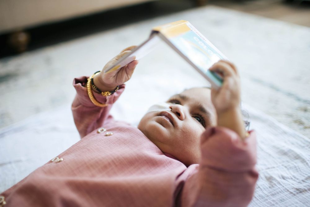 Mukilteo family photographer: a baby lays on the carpet and reads a book at a family photo session