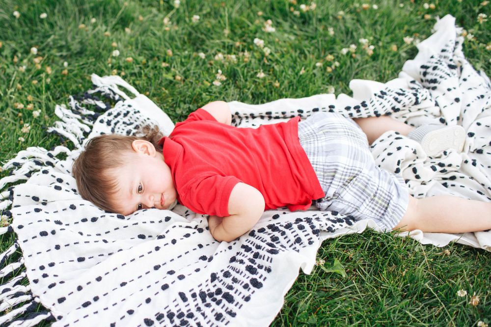 Seattle family photographer: A toddler lays down on a blanket in the lawn at a home photo session
