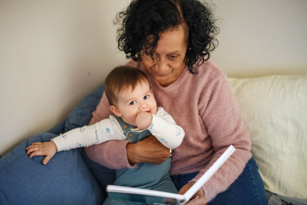 Seattle family photography at home: A toddler sits on his grandma's lap at a photo session