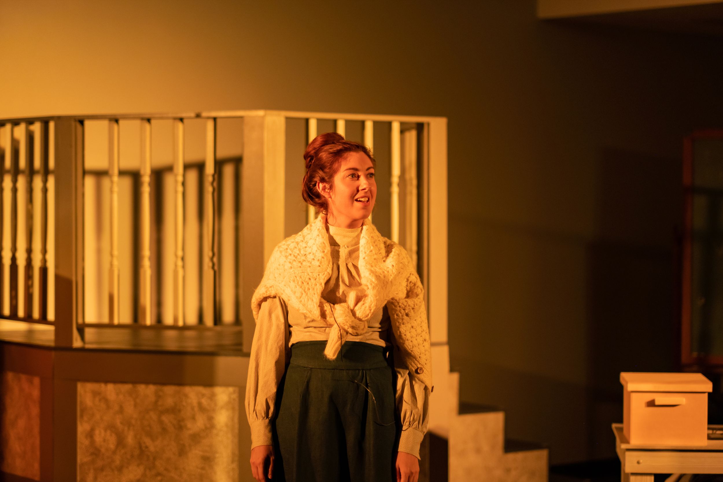 Stage performer in vintage attire illuminated by warm lighting in a theatrical scene.