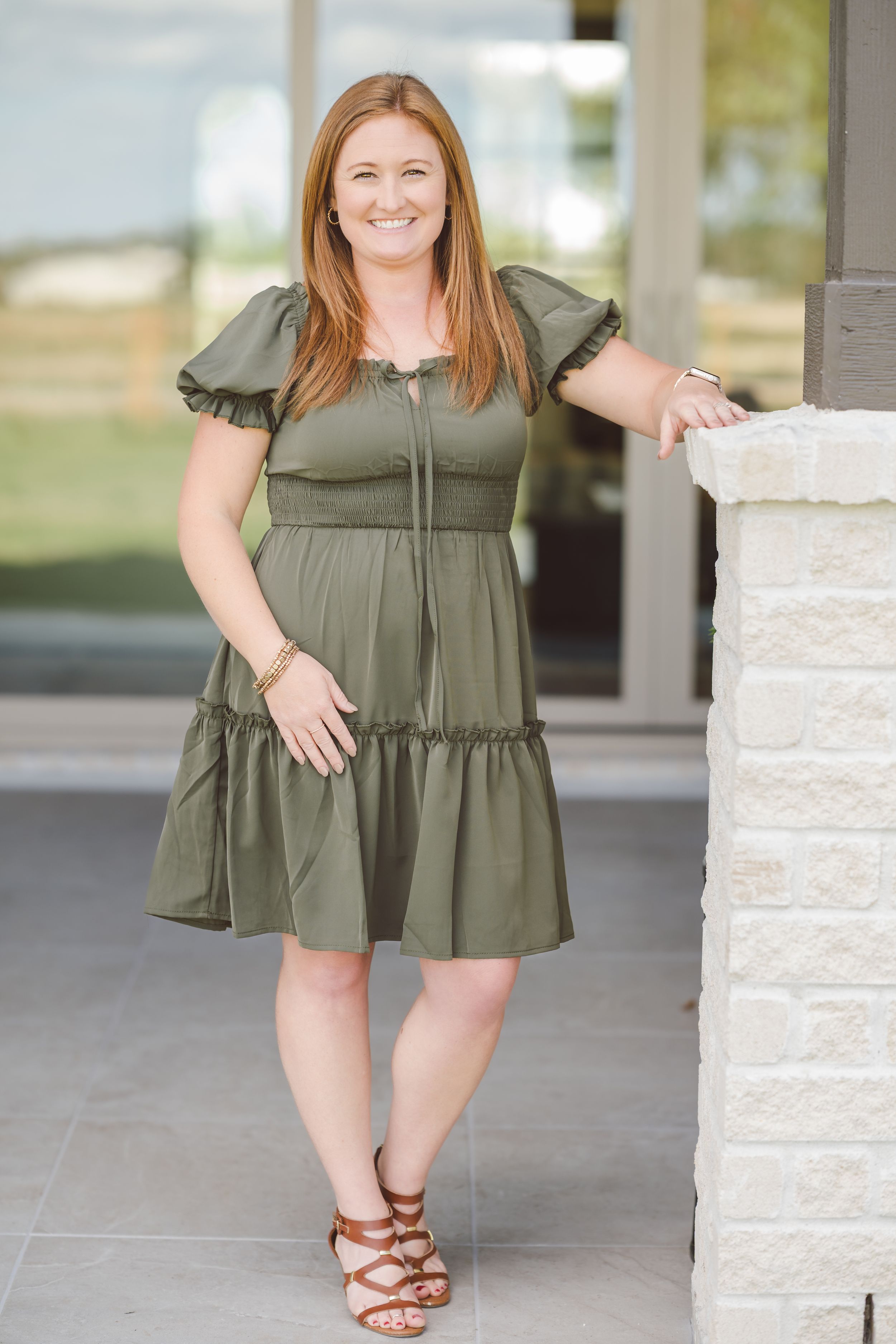 A collage of four photos showing someone in an olive green tiered dress posing against a stone wall outdoors.