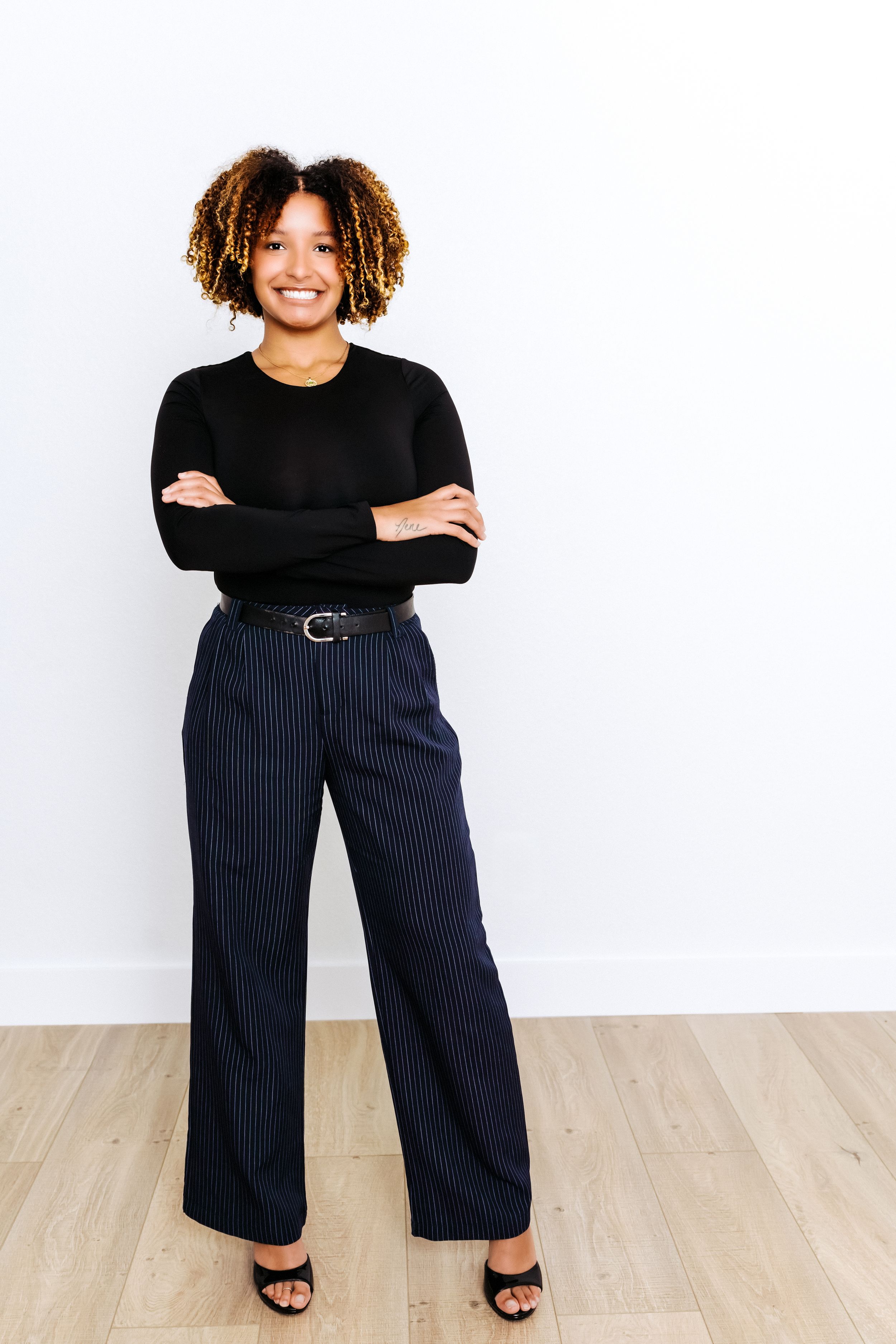 Three views of a person wearing a black top and navy pinstripe wide-leg pants with a belt and sandals.