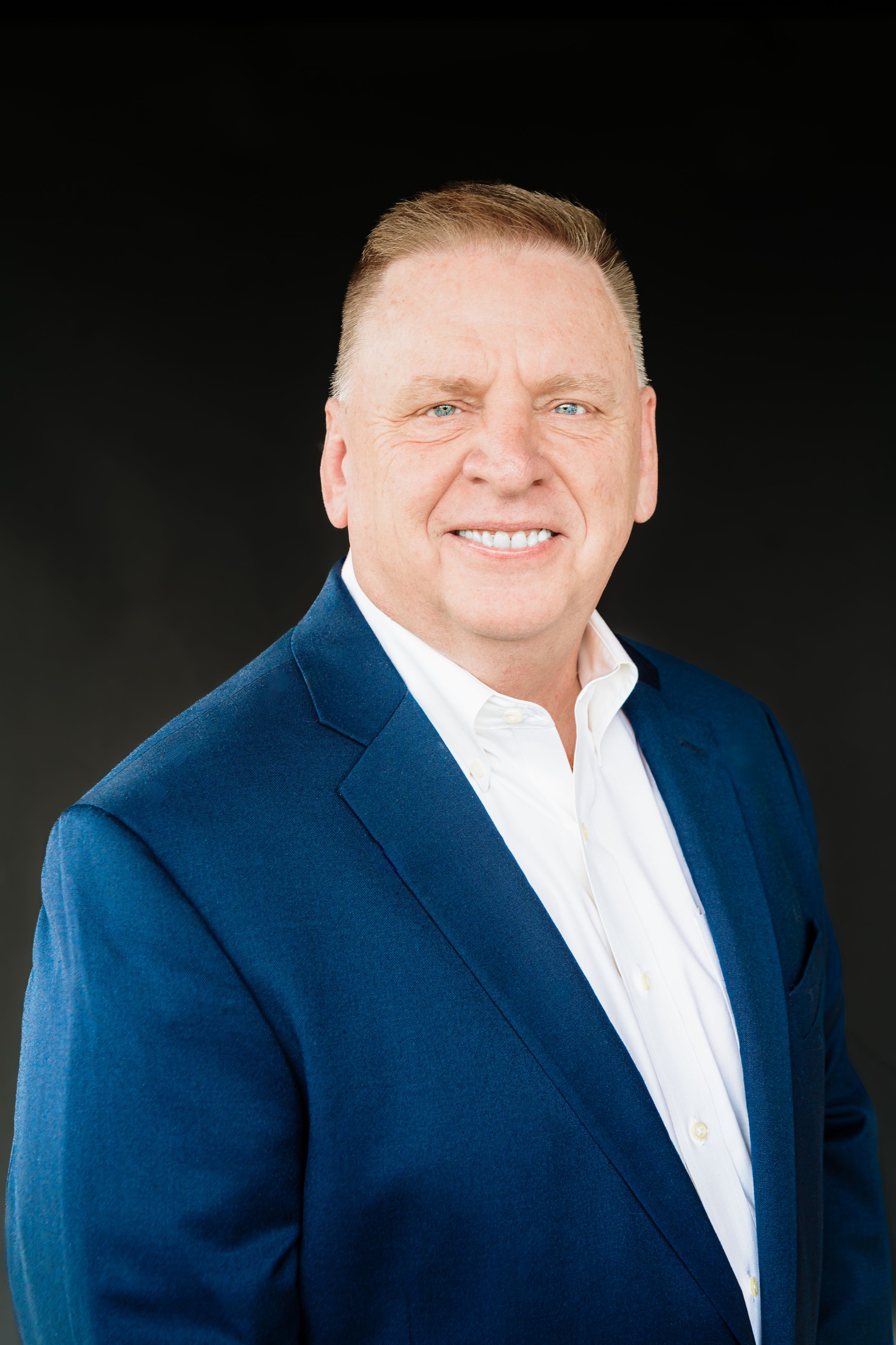 Professional headshot series showing person in navy blue blazer and white shirt against dark background.