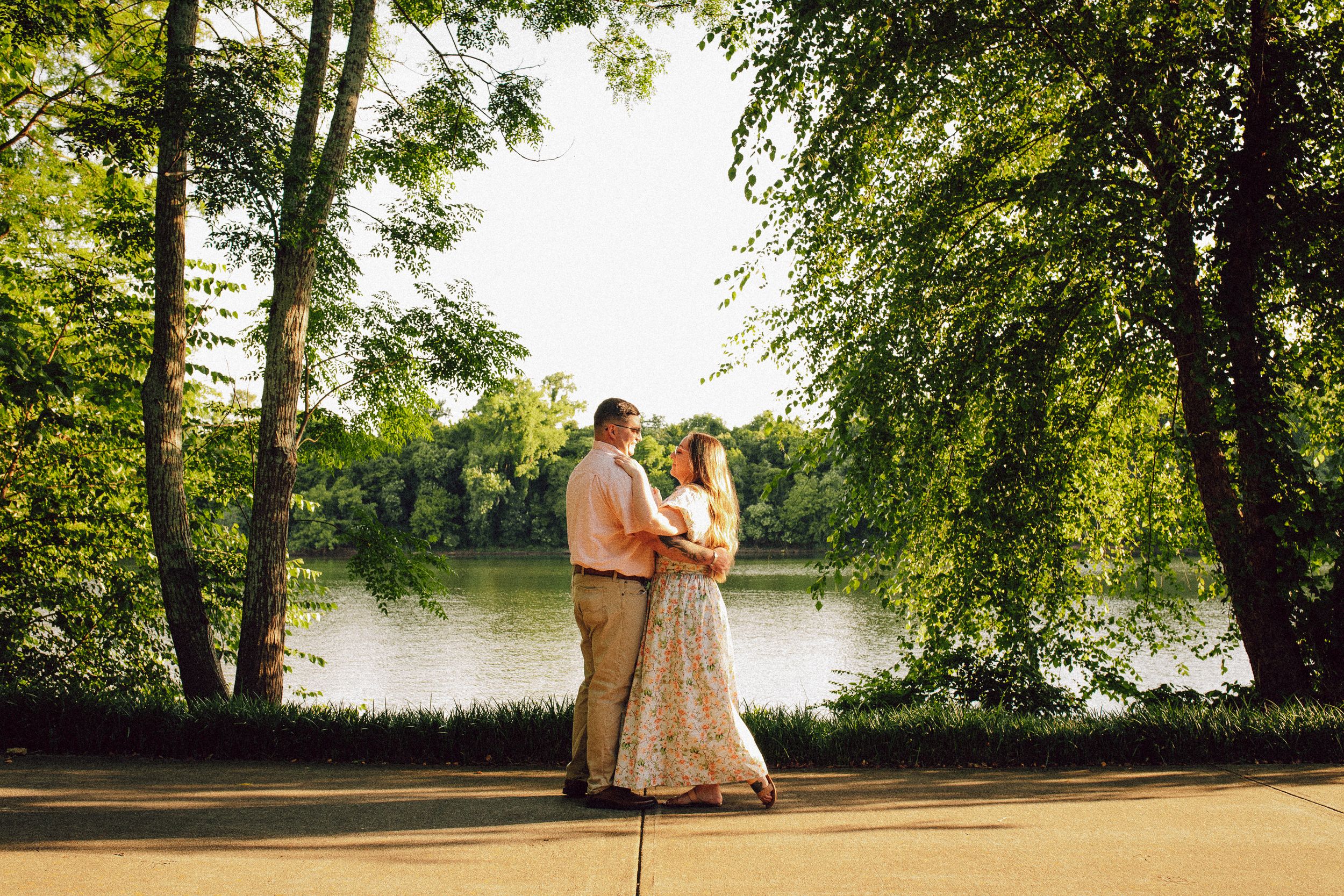 A tender moment captured between a couple by a scenic lake during golden hour.