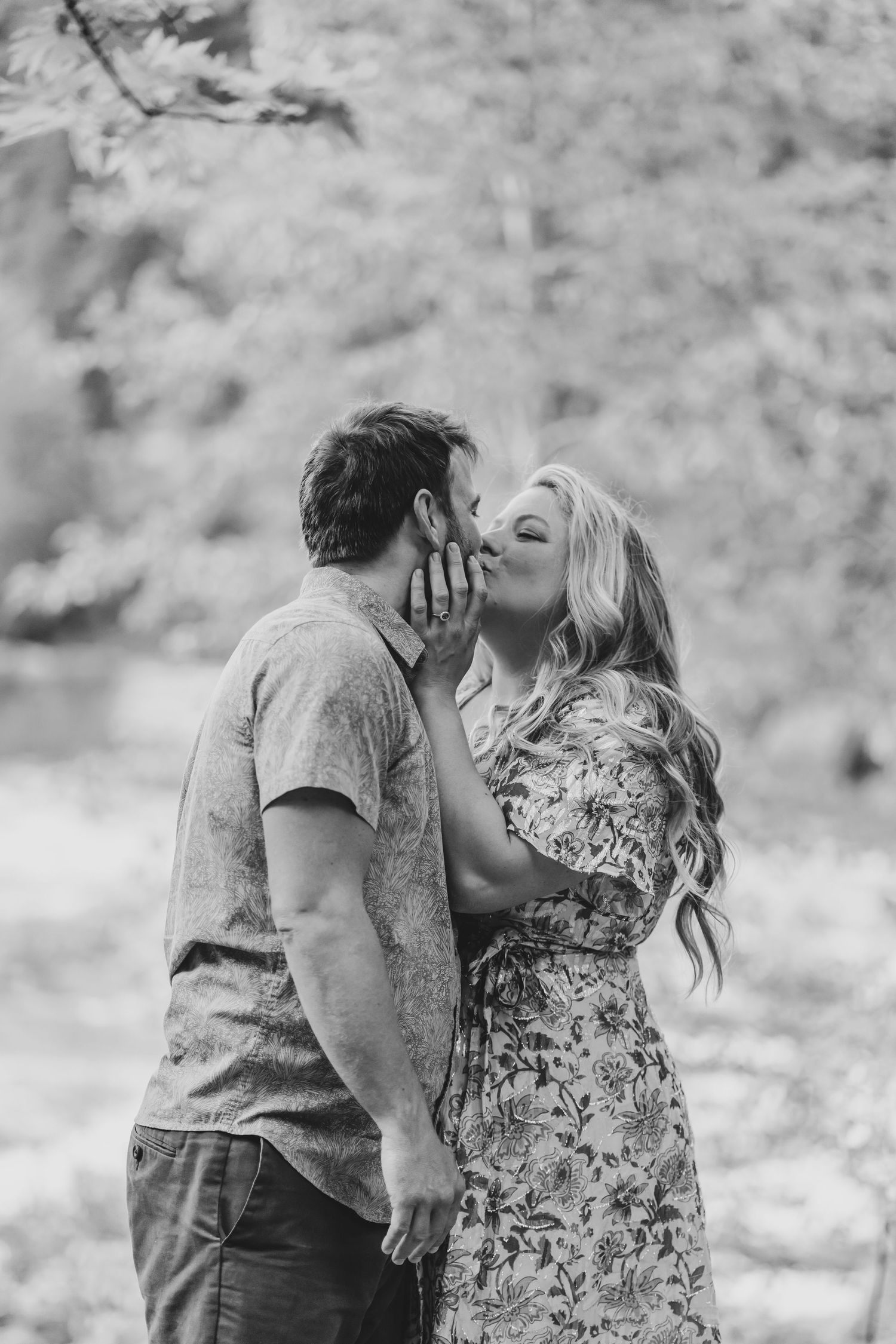 An intimate black and white portrait of a couple sharing a joyful moment outdoors.