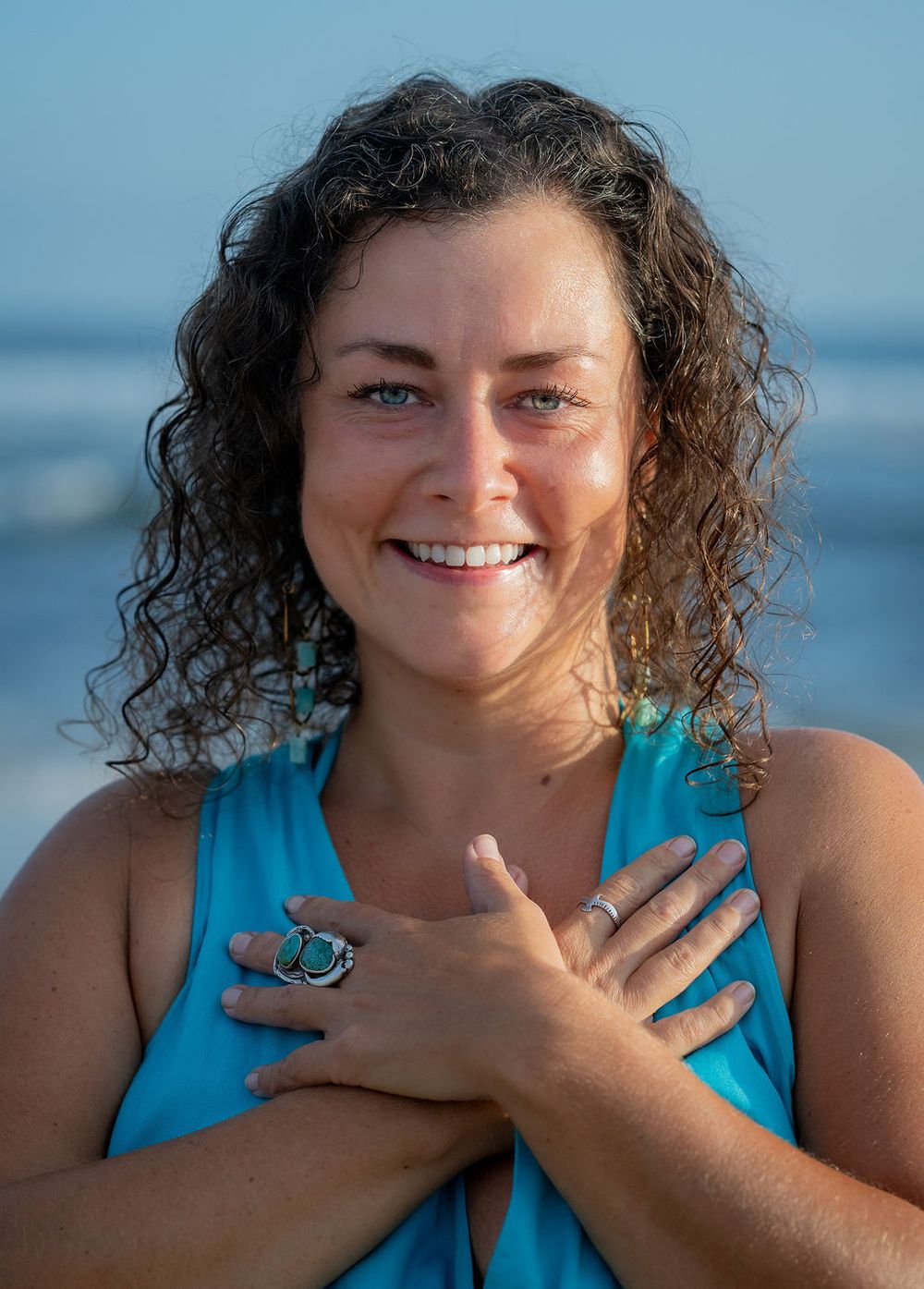Joyful outdoor portrait in turquoise attire at seaside.