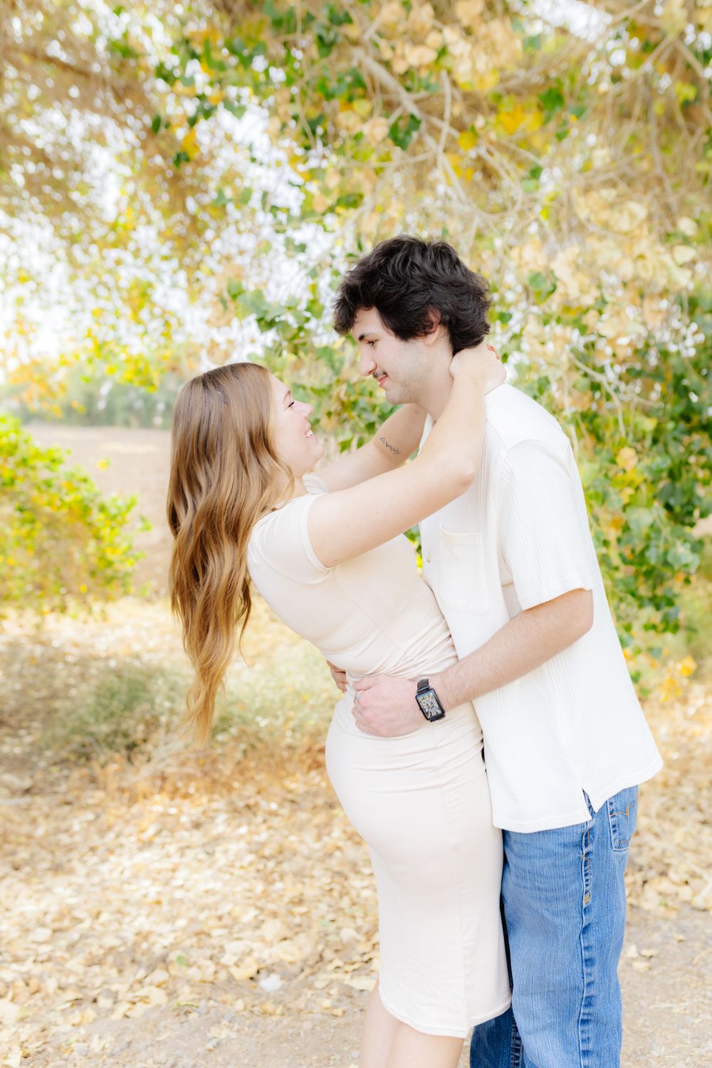 A young man holds his girlfriend by the waste, she wraps her arms around his shoulders.