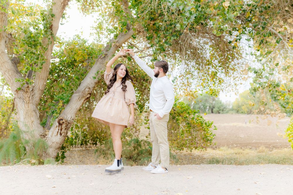 A young couple gaze lovingly into each other's eyes. Her dress flares out as he twirls her in a circle.