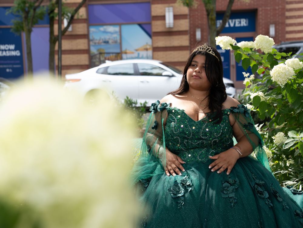 An elegant emerald ball gown captured in a garden setting with white hydrangeas in the foreground.