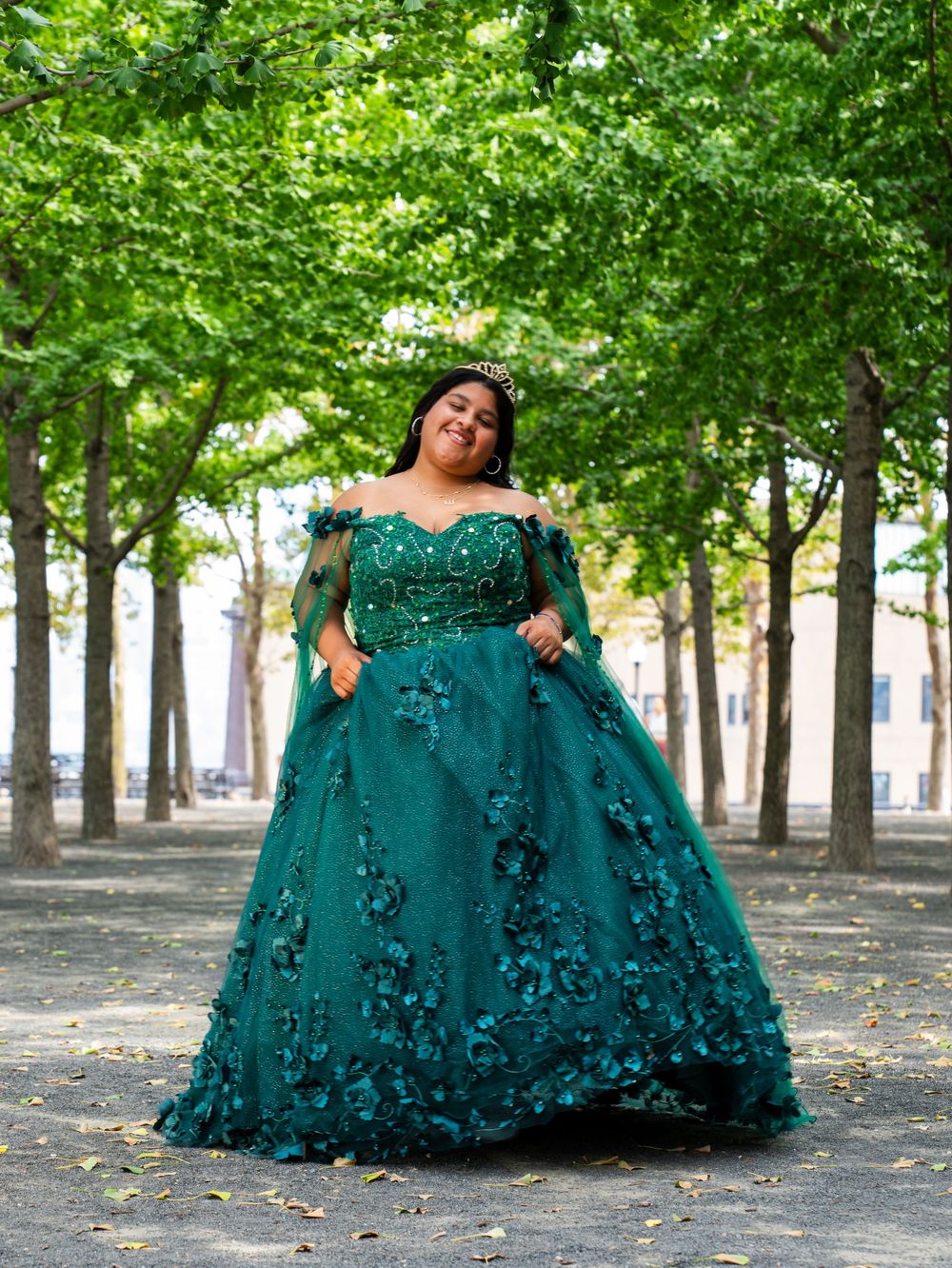 A dramatic emerald ball gown photographed in an avenue of green trees.