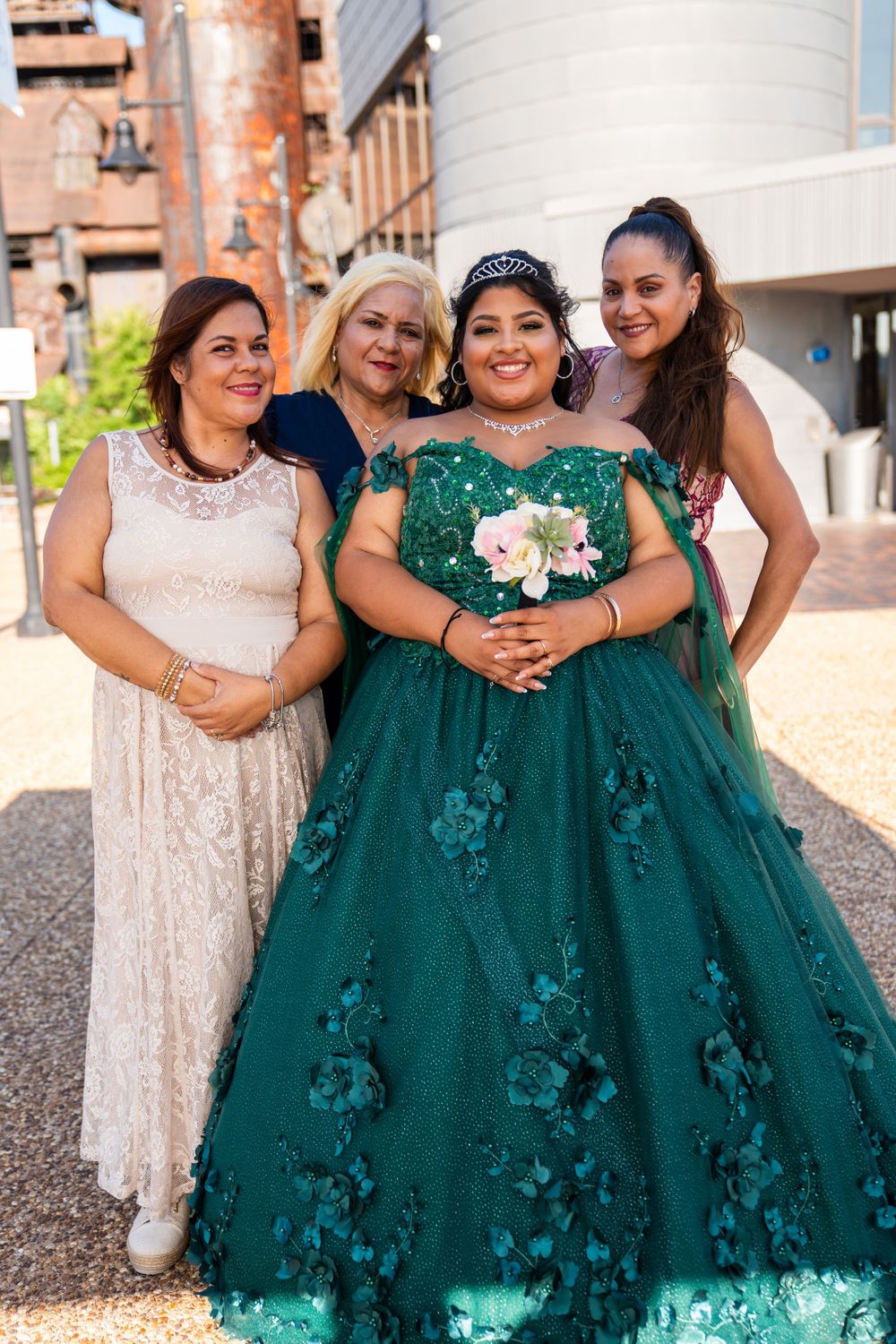 A group photo showing four people in formal attire with an emerald green ball gown as the centerpiece.