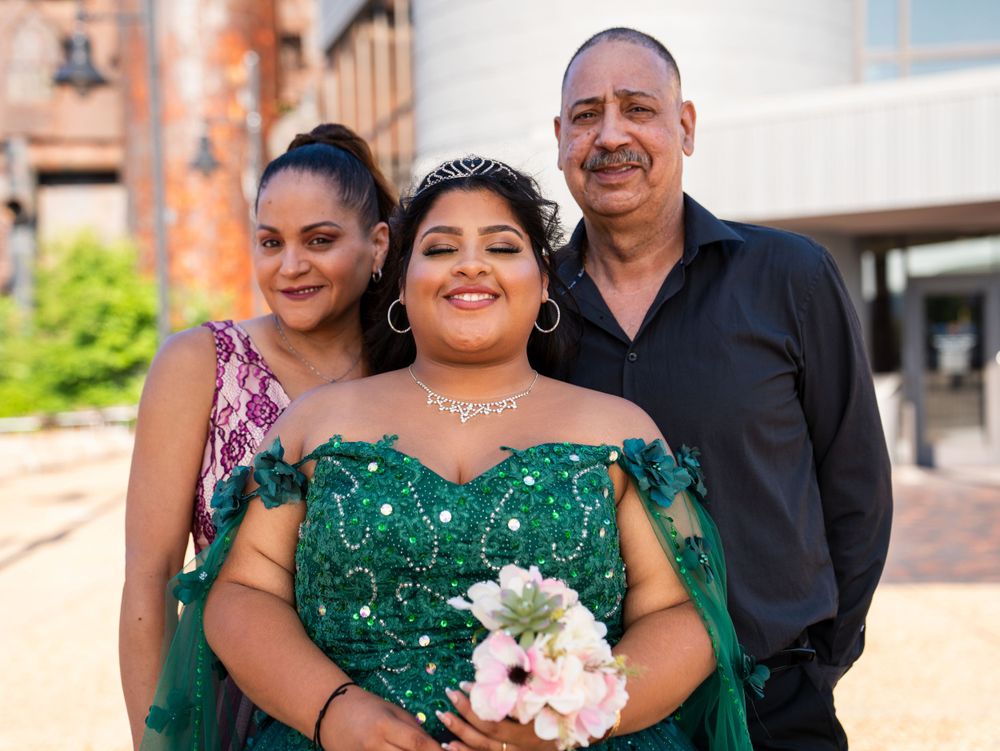 Three people pose together for a formal portrait against a brick building backdrop.