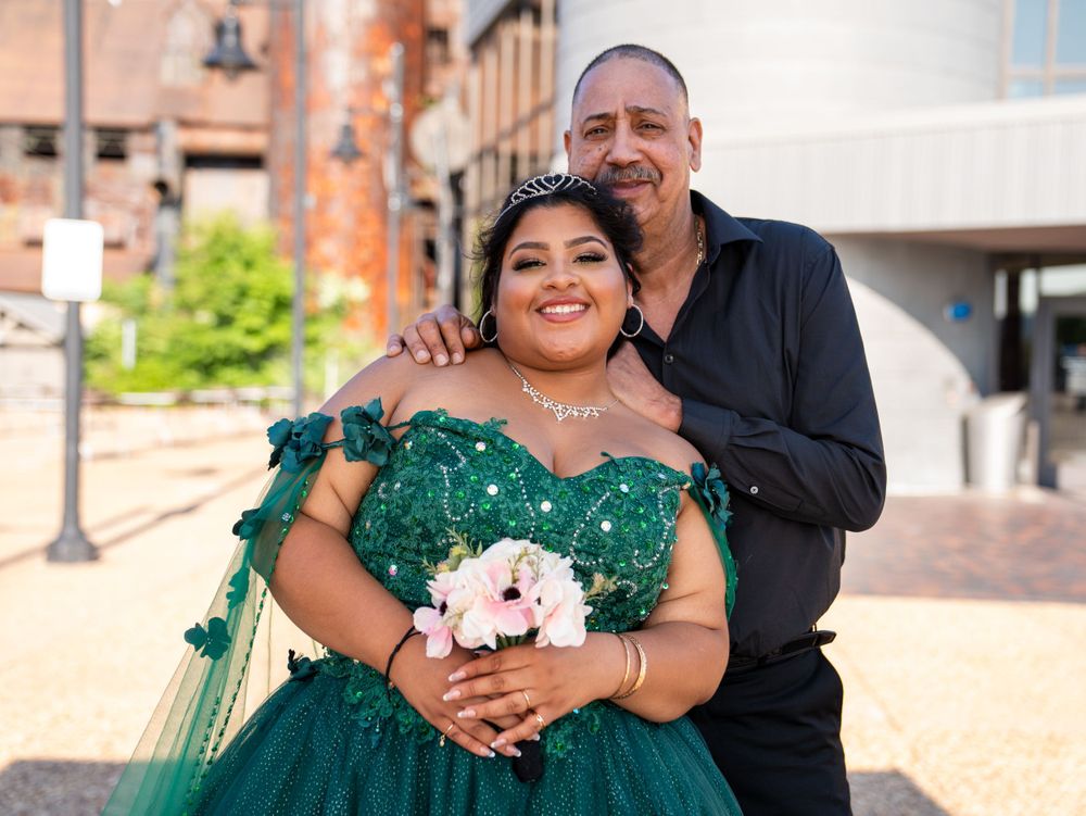 A formal portrait of two people against an urban backdrop with brick buildings.