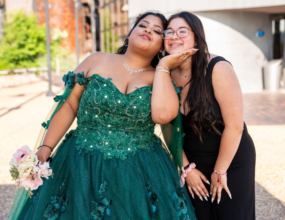 Two people sharing a joyful moment together, one wearing an emerald green ball gown.
