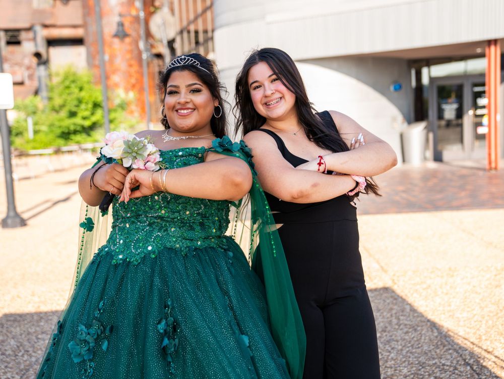 Two people posing together outdoors, one wearing a stunning emerald green ball gown.