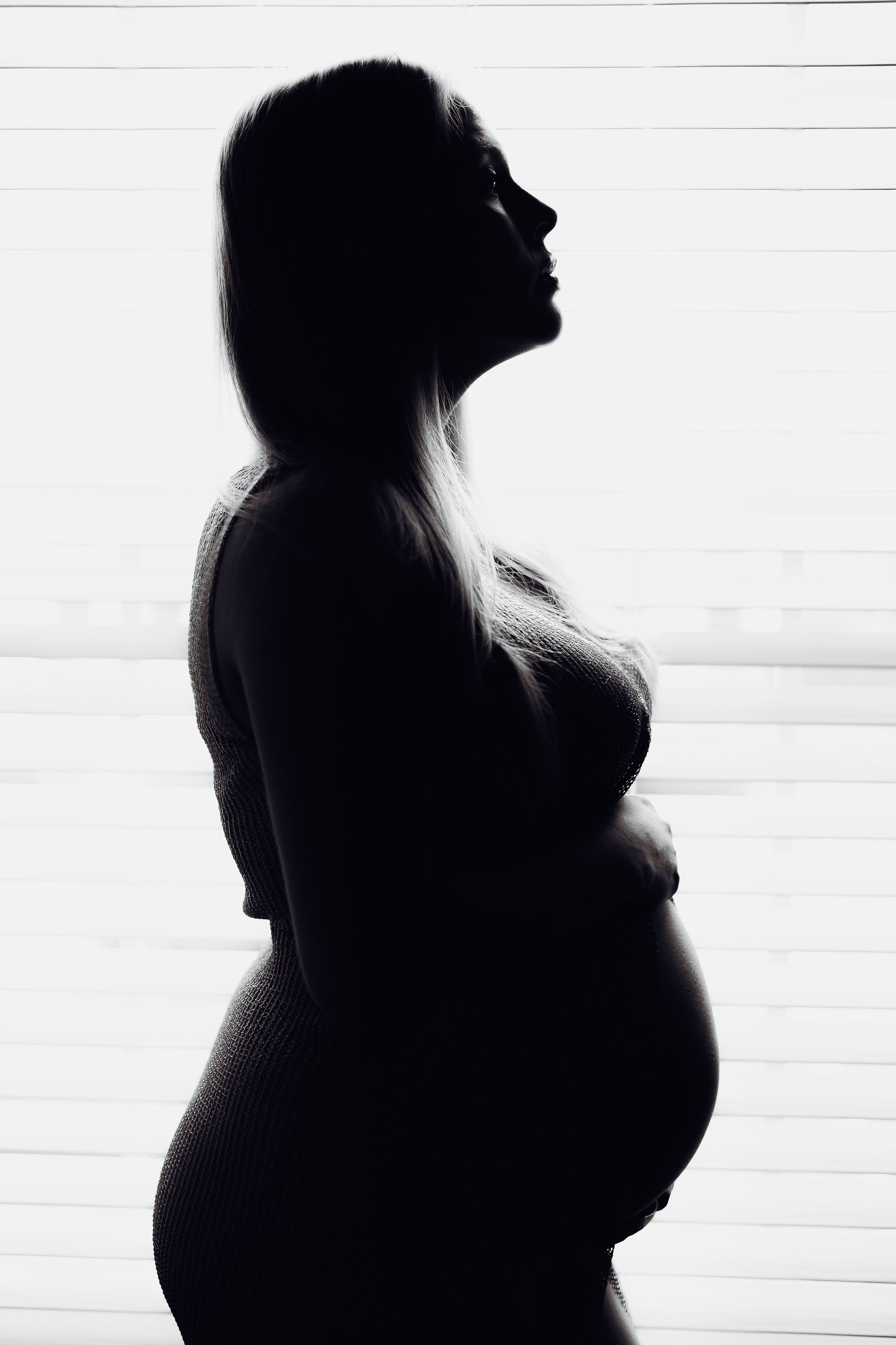 Silhouette profile of pregnant woman against white background.