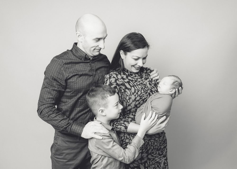 Black and white family portrait showing tender moment with children.
