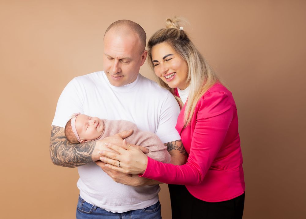 Family portrait against beige background showing tender moment together.