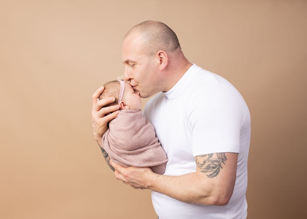 Tender moment captured during professional family photo session against neutral backdrop.