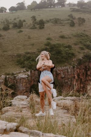 man swinging woman around on mountain