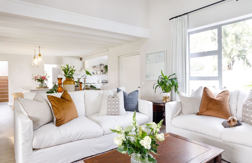 Coastal style living room with white sofas, cognac pillows and fresh flowers on coffee table.