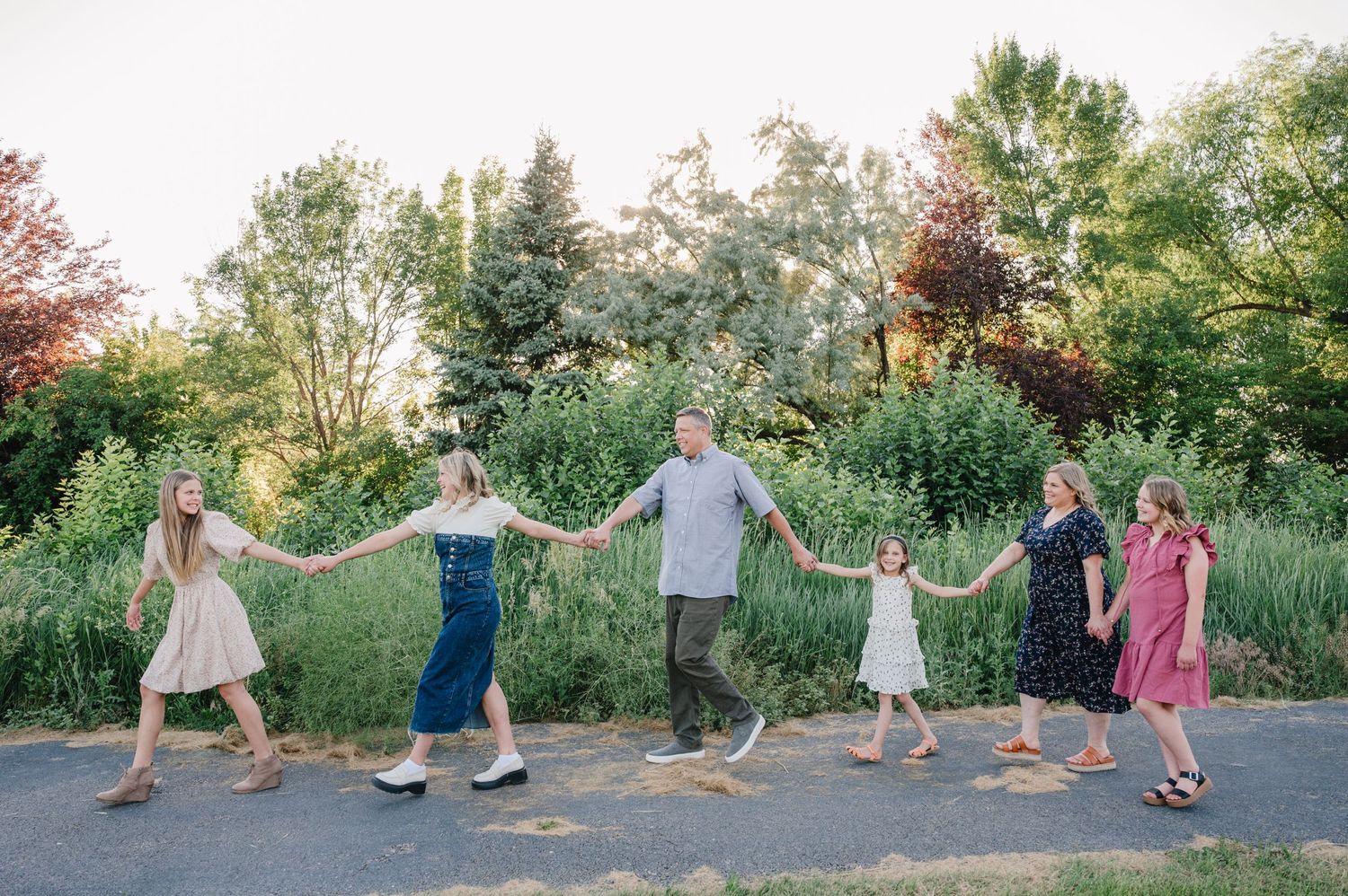 A family holds hands in a line while dancing outside during golden hour.