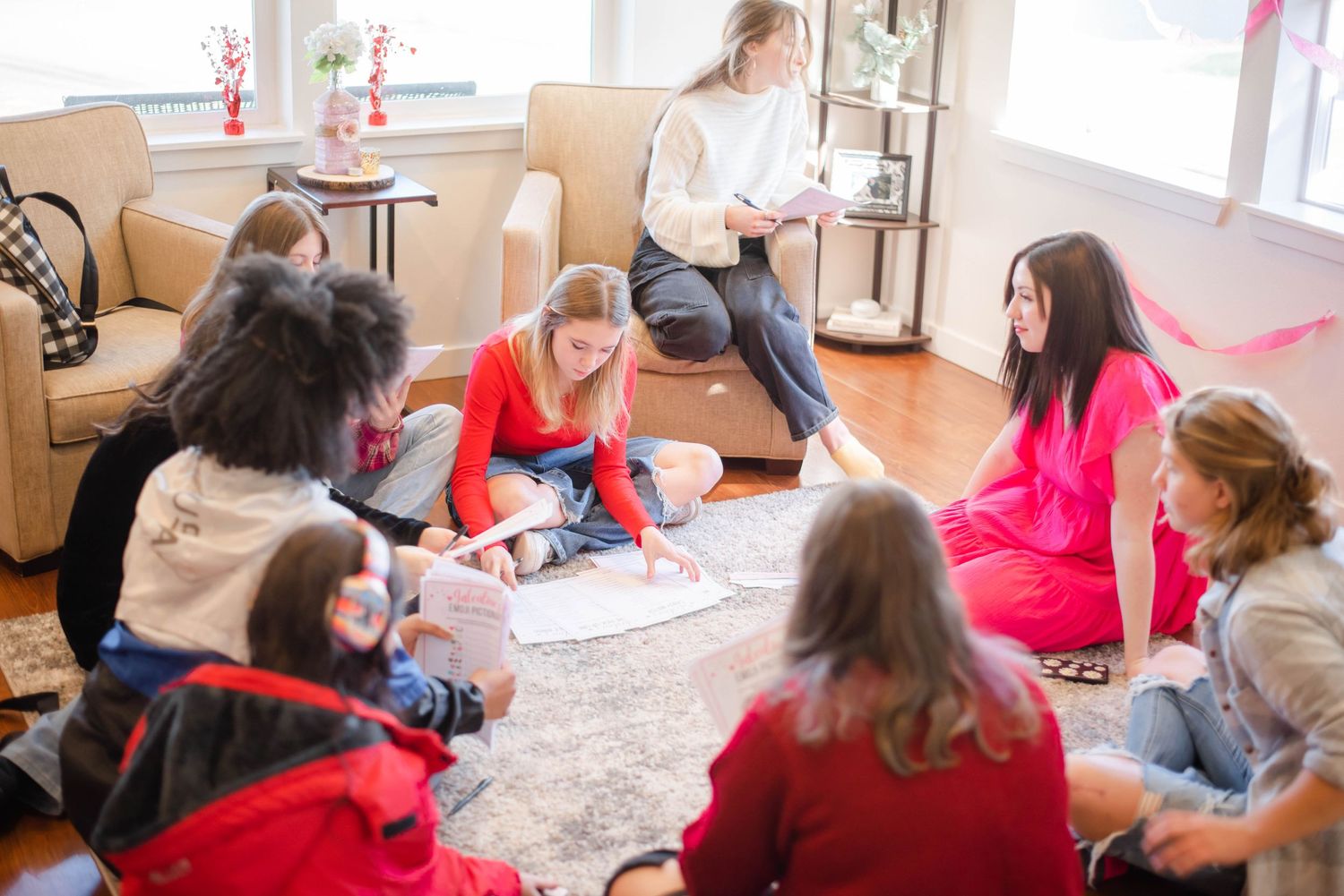 Group gathering on carpeted floor with festive red decorations.