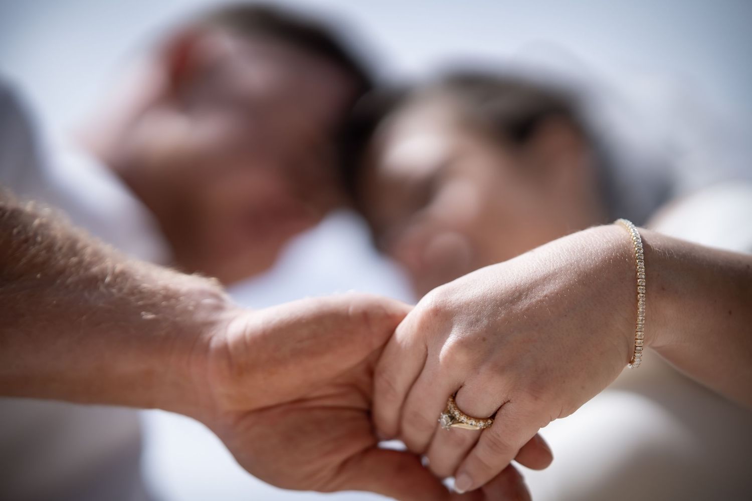 Close-up detail of hands with wedding rings in soft focus.