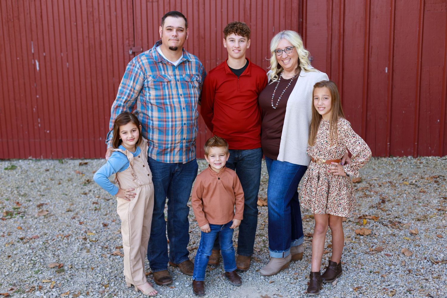 Posing family in front of a red barn wall.