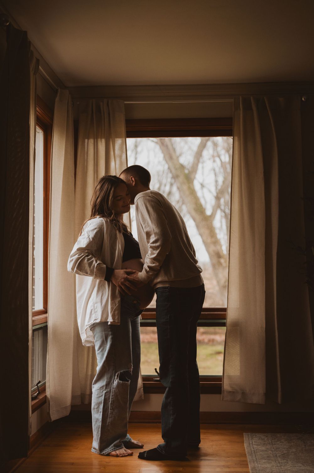 Intimate silhouette of couple by window in warm natural lighting.