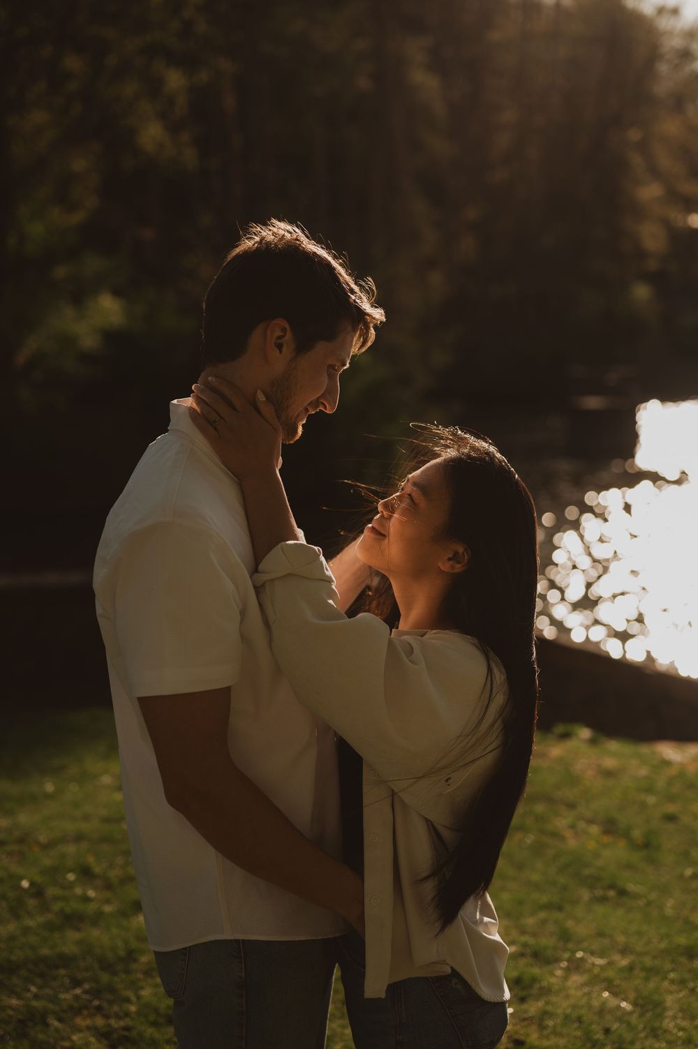 Romantic couple embracing in warm sunlight by waterfront.