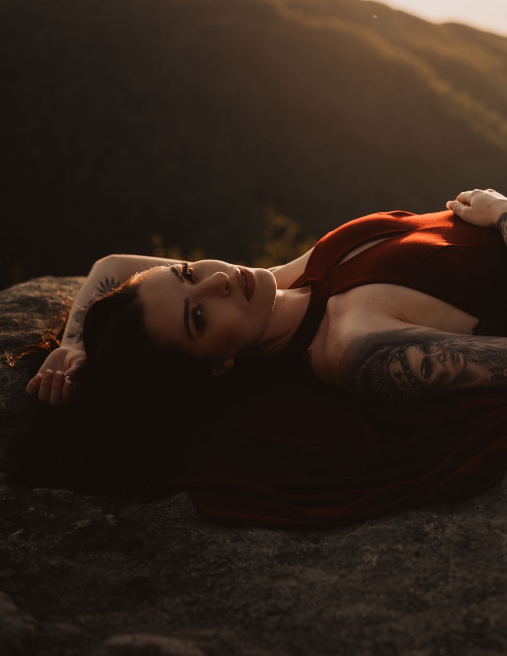 Silhouette of someone reclining against scenic mountain backdrop at golden hour creating dramatic contrast.