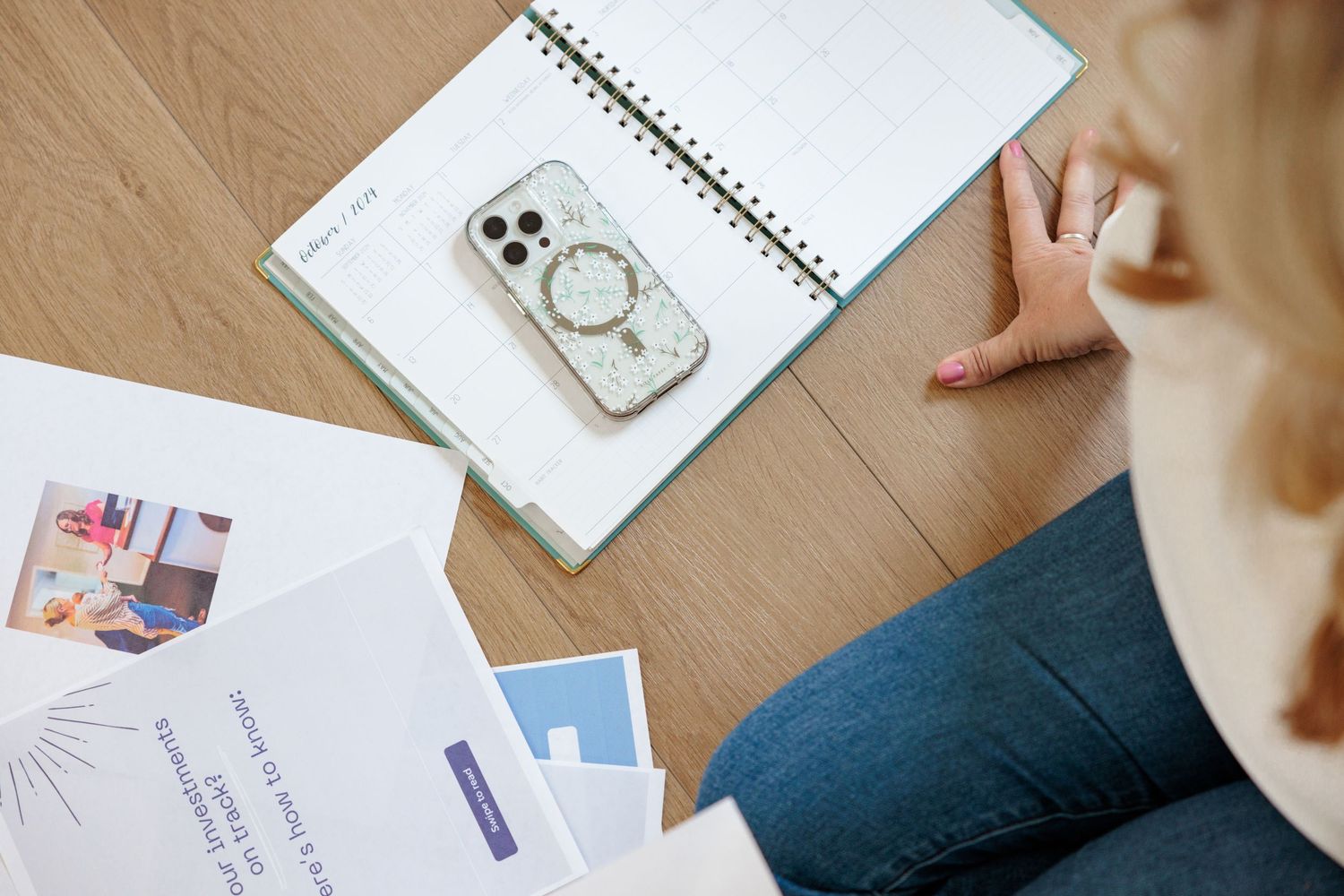 Overhead view of notebooks, papers and office supplies arranged on a wooden desk surface.