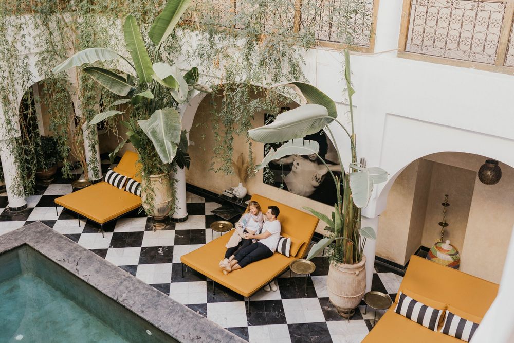 Modern lounge area with checkerboard floor, striped cushions and tropical plants.