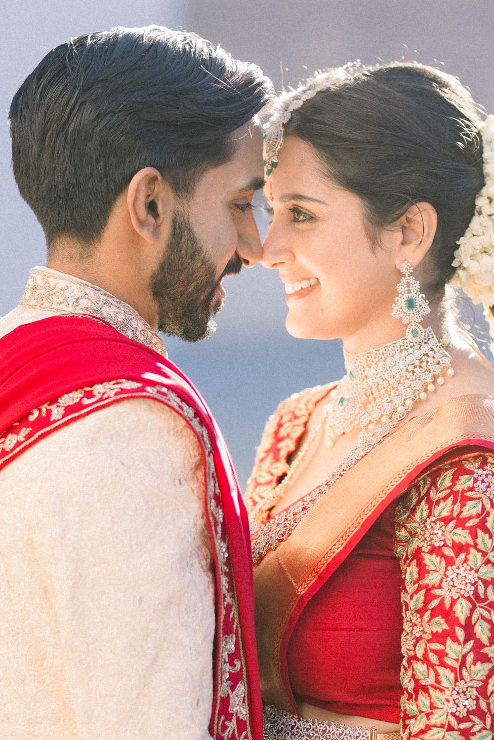 Traditional South Asian wedding couple share intimate moments in ornate red and gold attire.