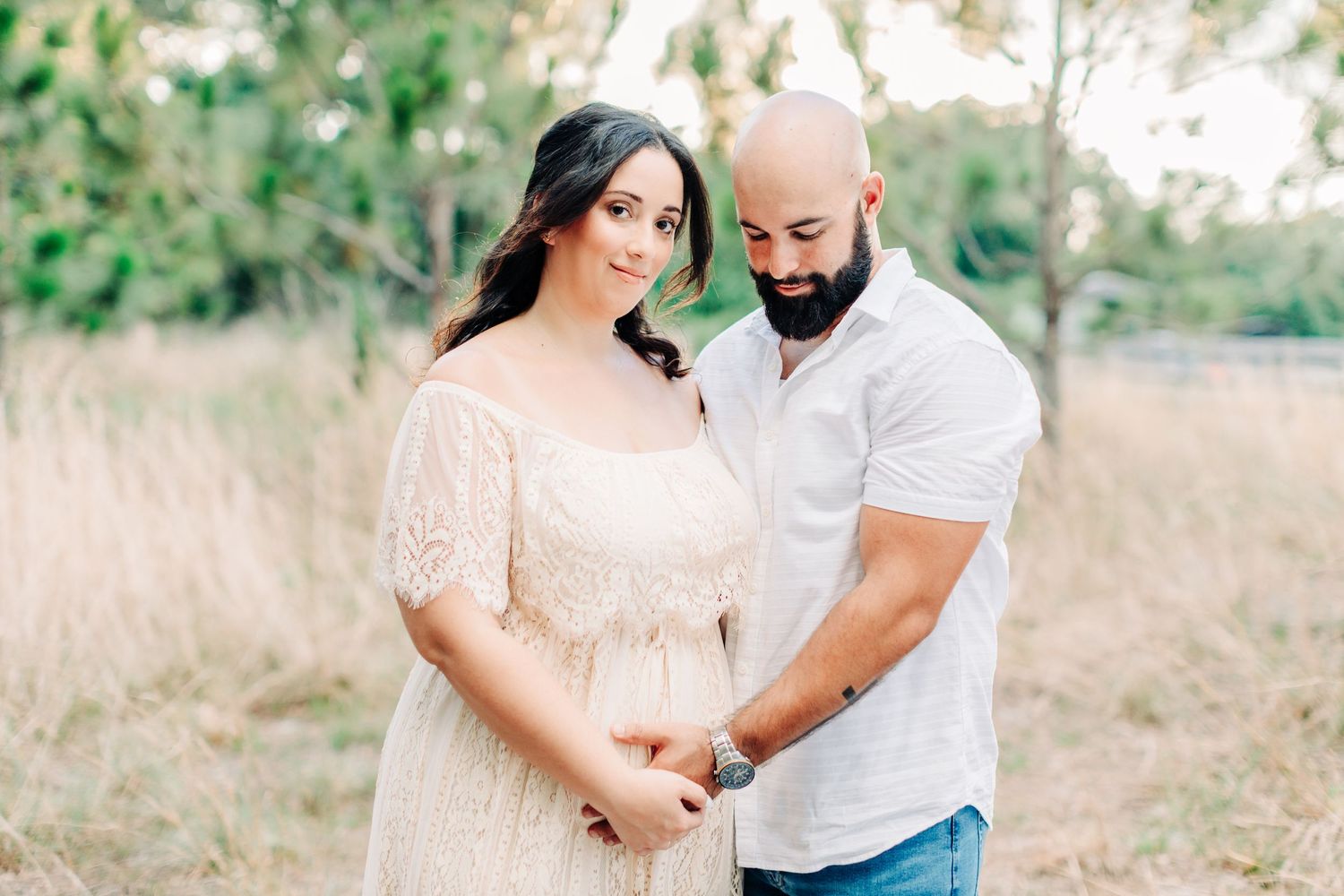 Expecting couple standing close together in beautiful natural surrounding during pregnancy announcement session in Orlando