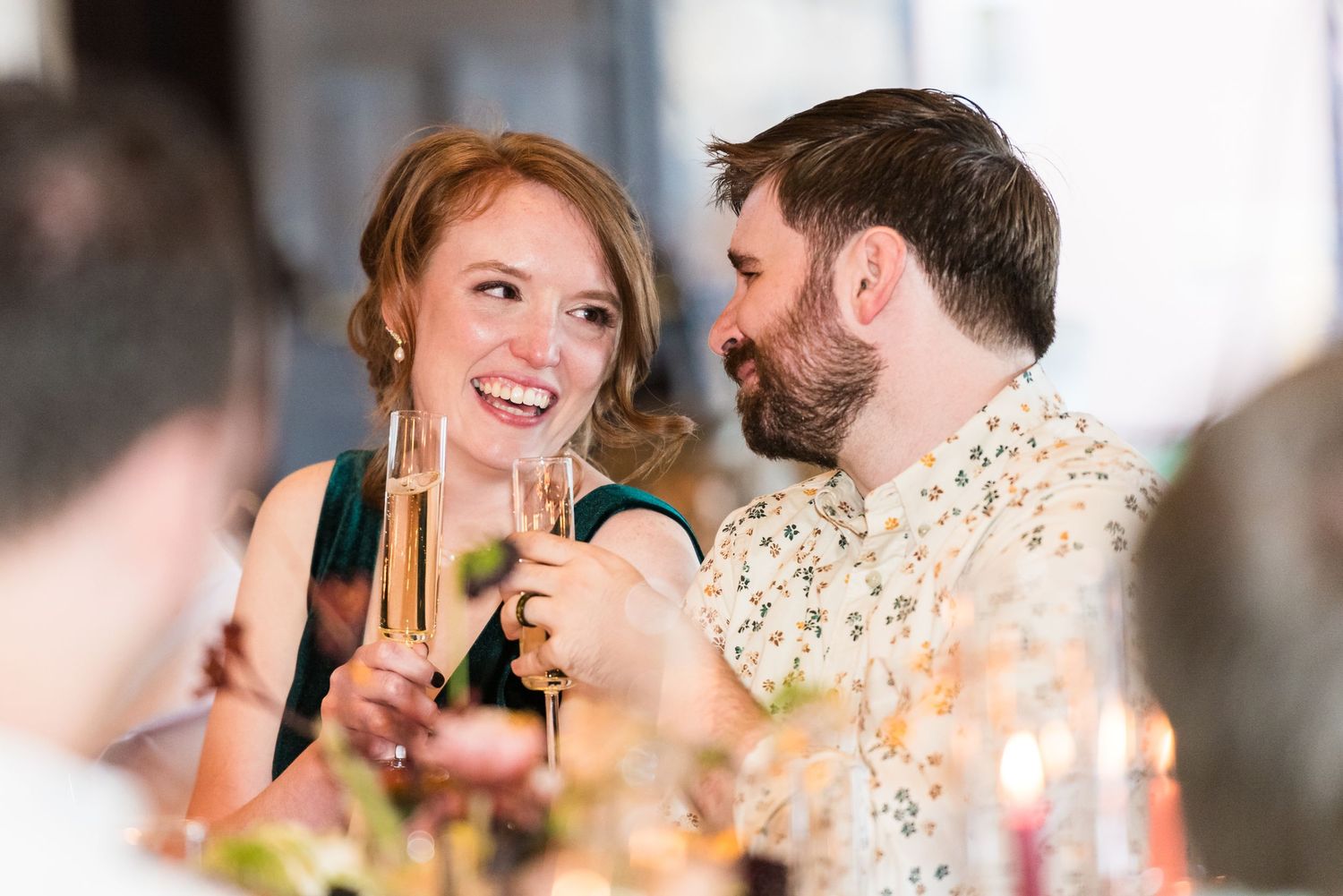 A couple shares a romantic toast with champagne glasses at an elegant reception dinner.