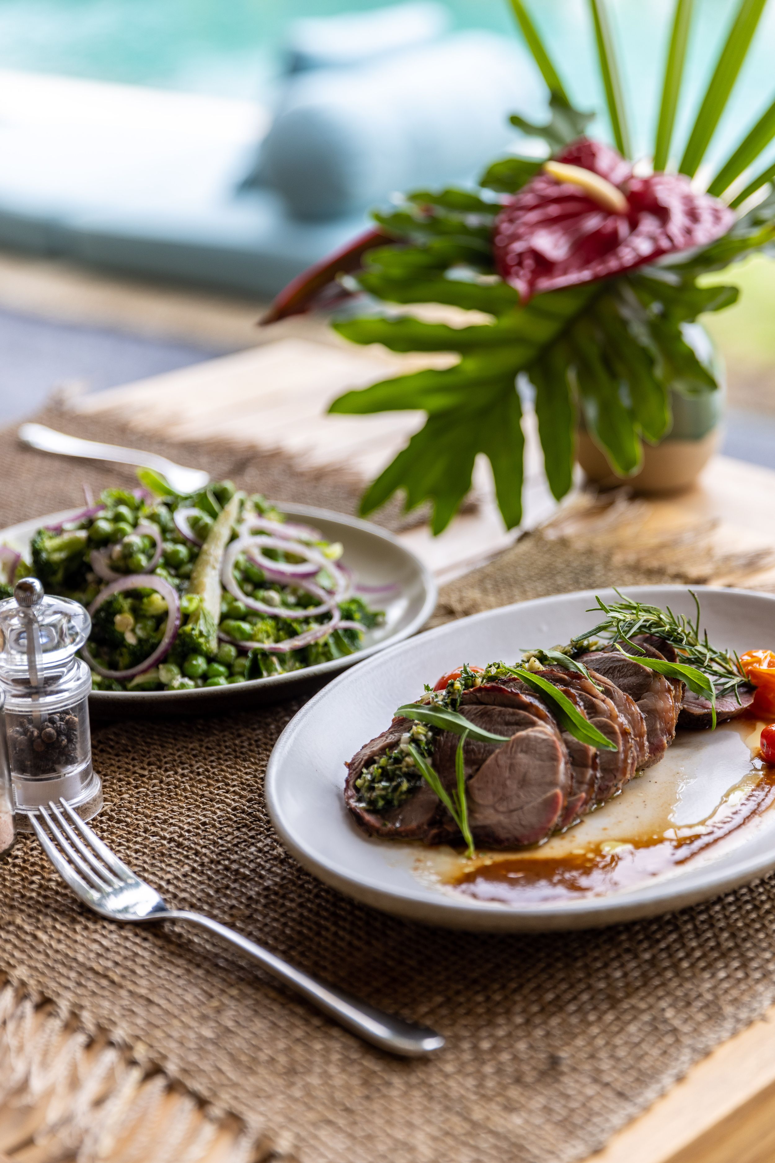 Plated seared tuna steak with green garnish on rustic table setting.