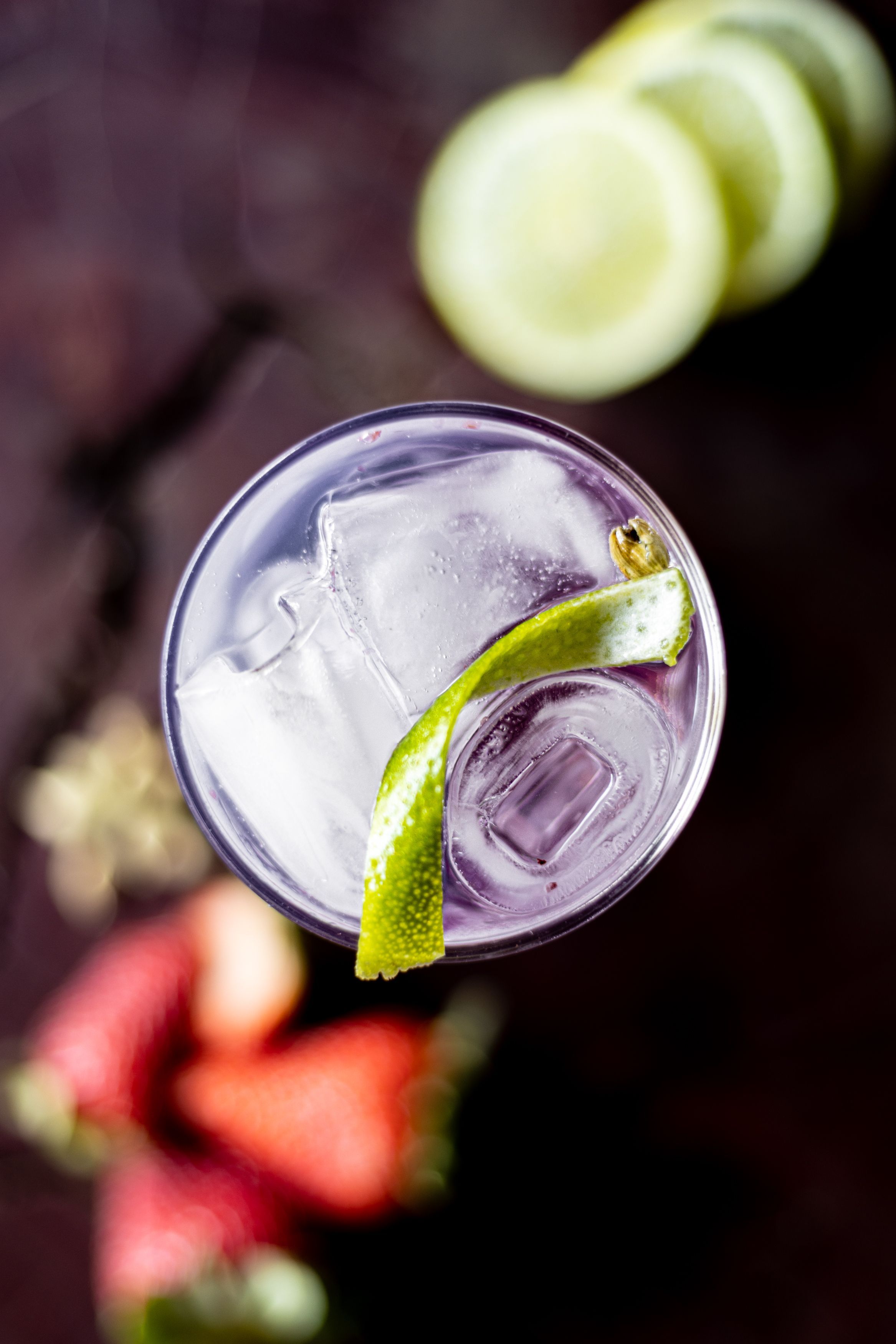 Refreshing cocktail with ice and lime garnish in a tall glass viewed from above.