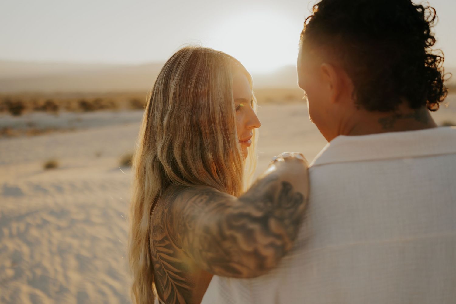 Romantic sunset portrait of couple against desert backdrop.