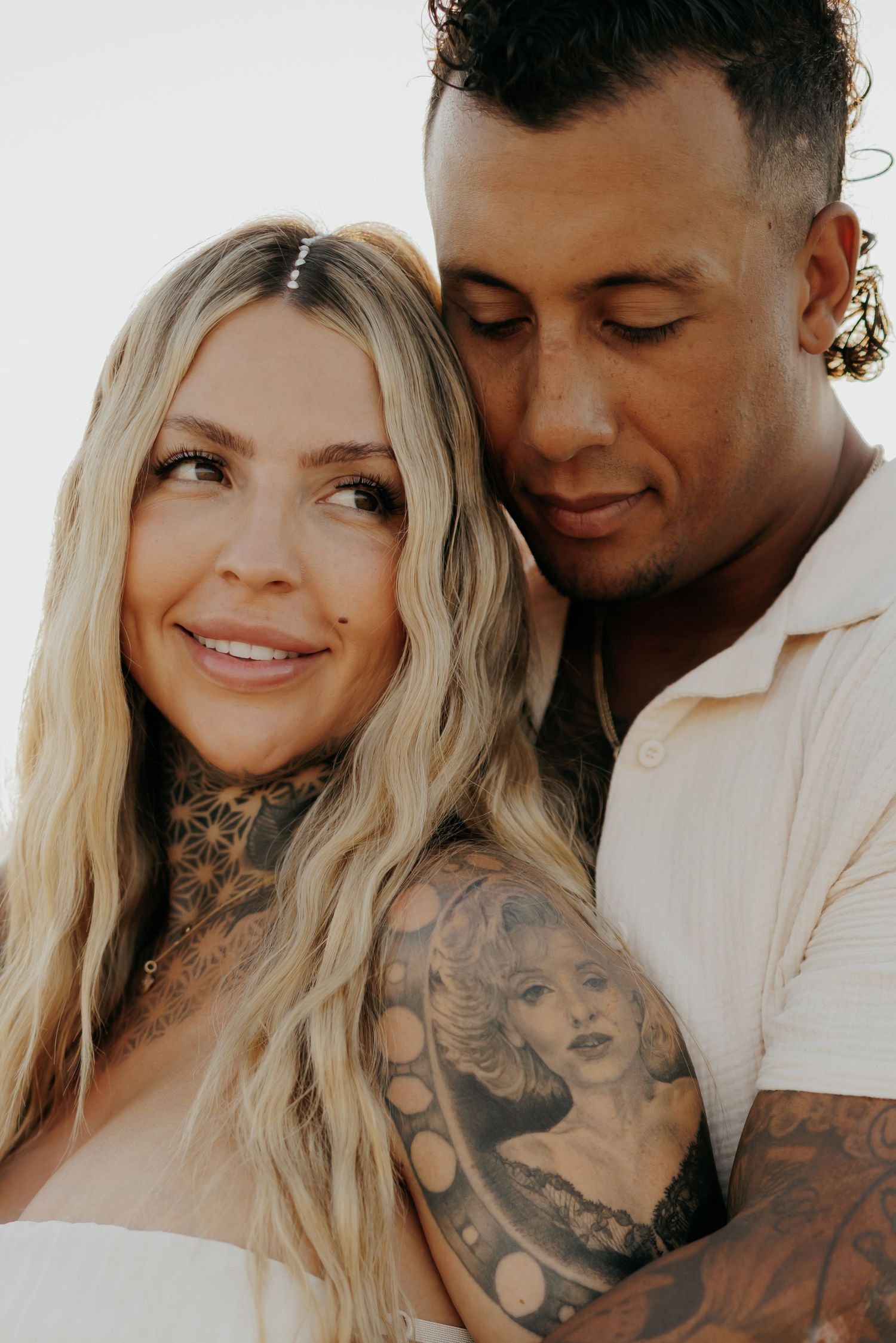 Close-up portrait of couple in white clothing during desert maternity shoot.