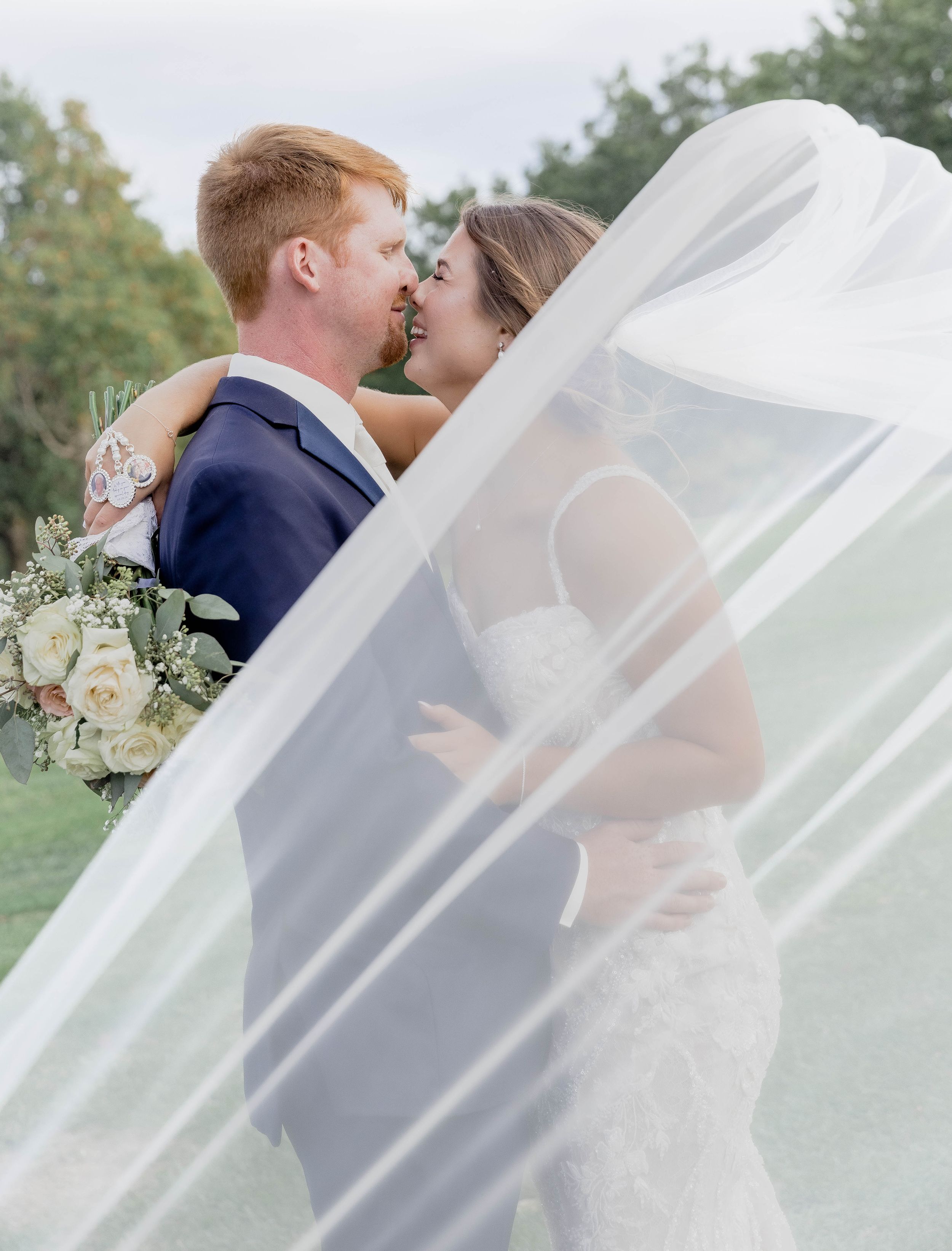 Ethereal wedding portraits with flowing veil captures romantic moments between newlyweds outdoors.
