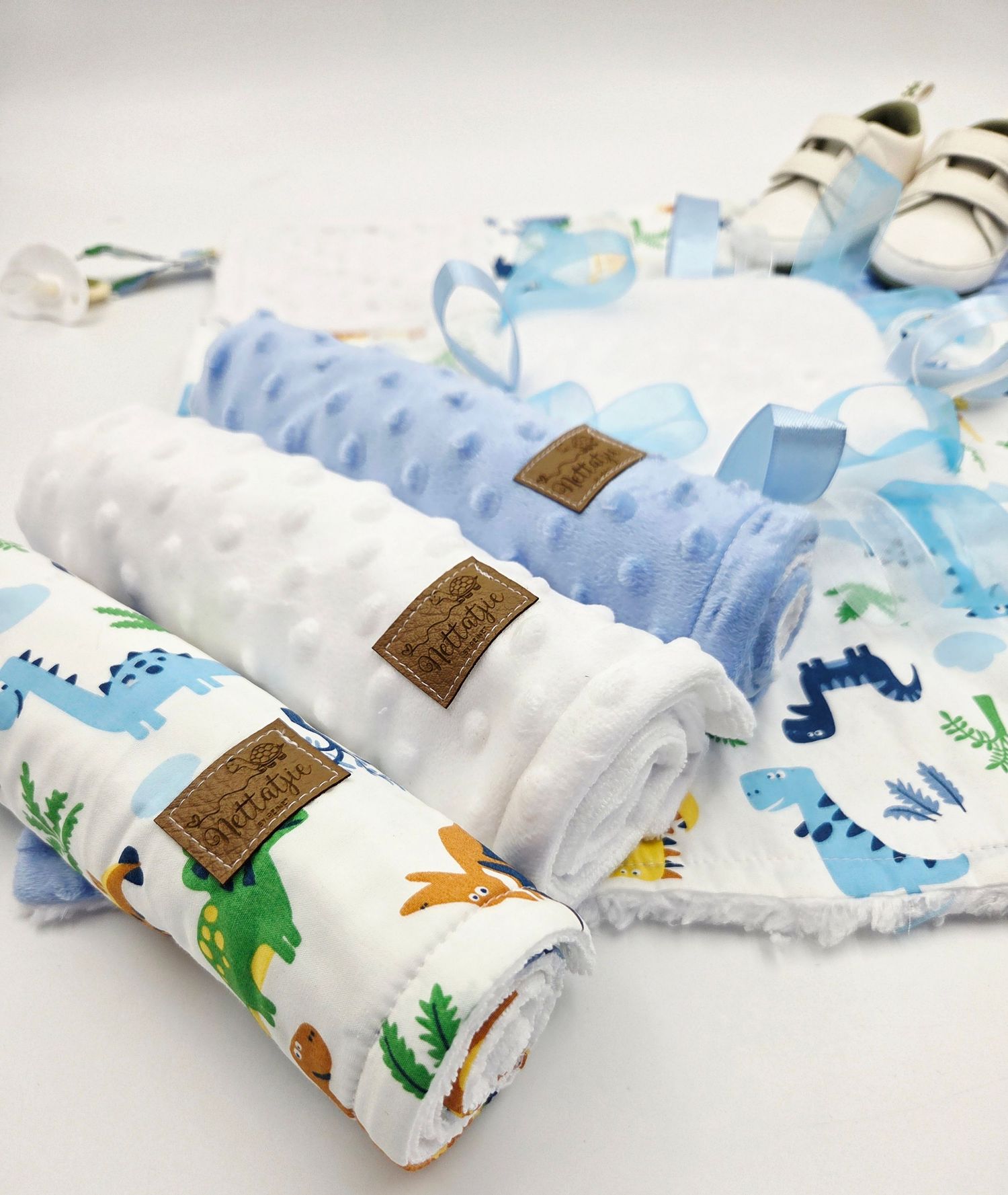 Soft baby blankets with dinosaur prints and minky fabric in blue and white colors arranged in a row.
