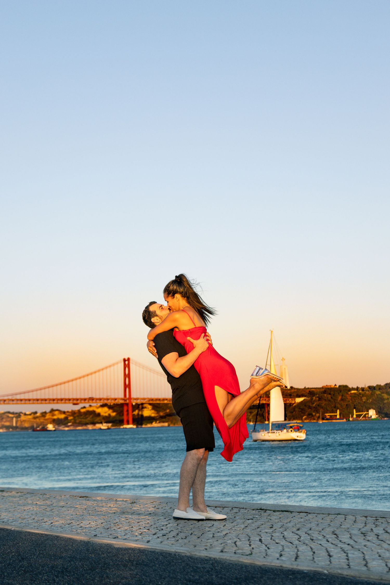 A romantic couple embraces against the backdrop of the Golden Gate Bridge in San Francisco during sunset.