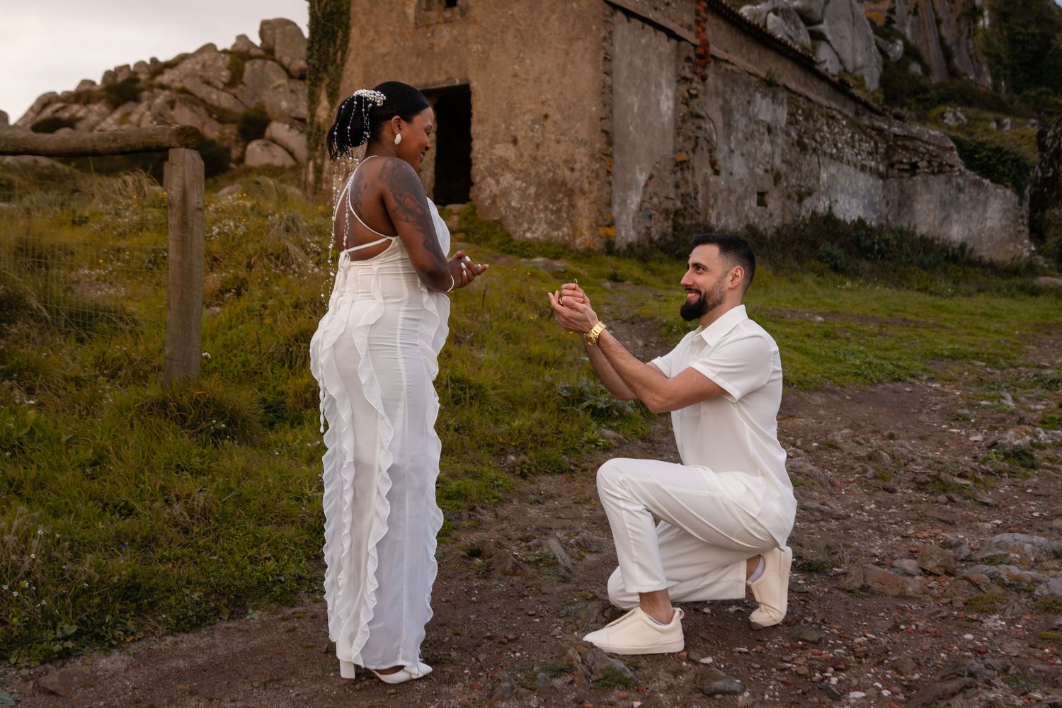 A surprise proposal moment against a rustic stone building backdrop.