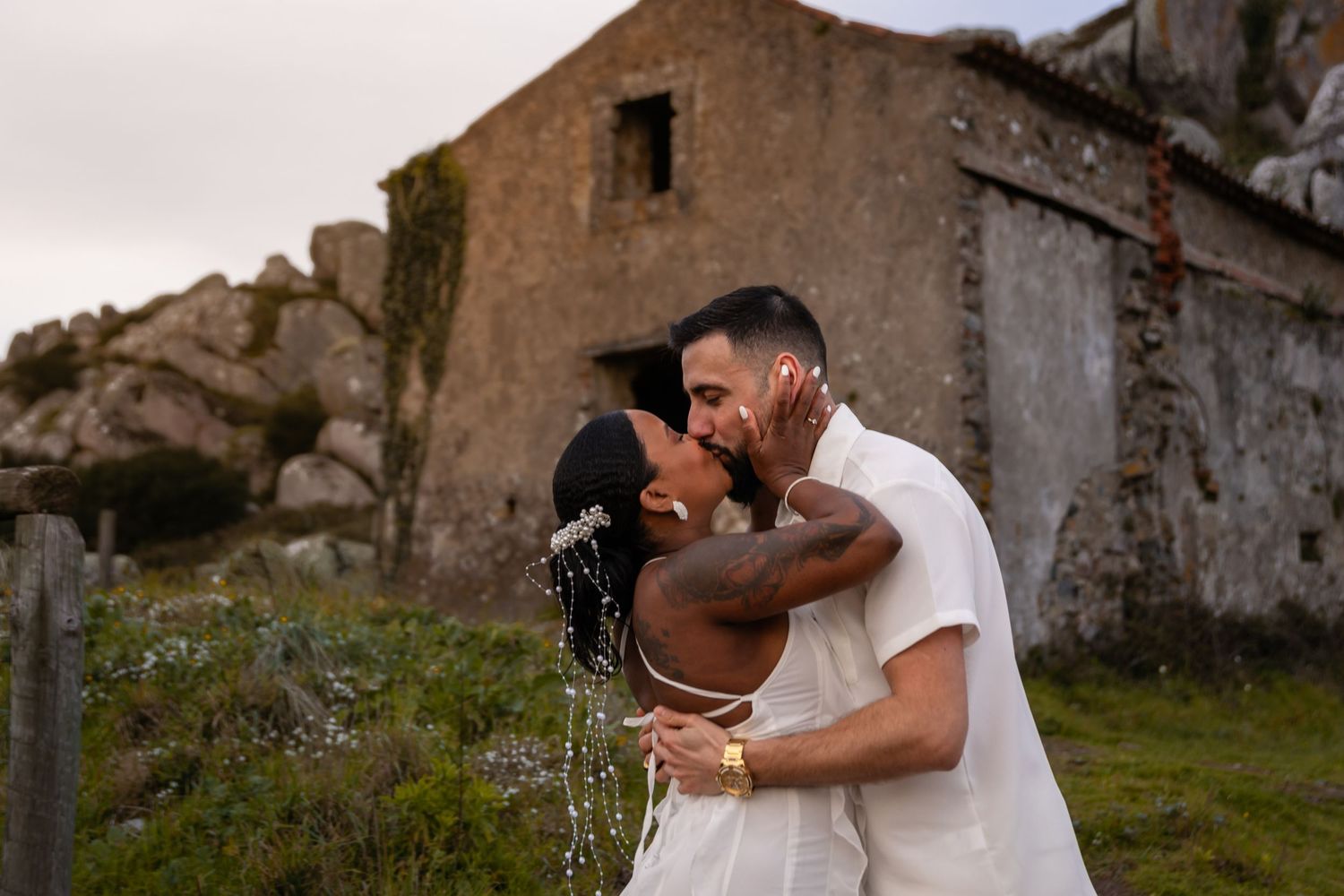 A romantic embrace following a proposal near an old stone building.