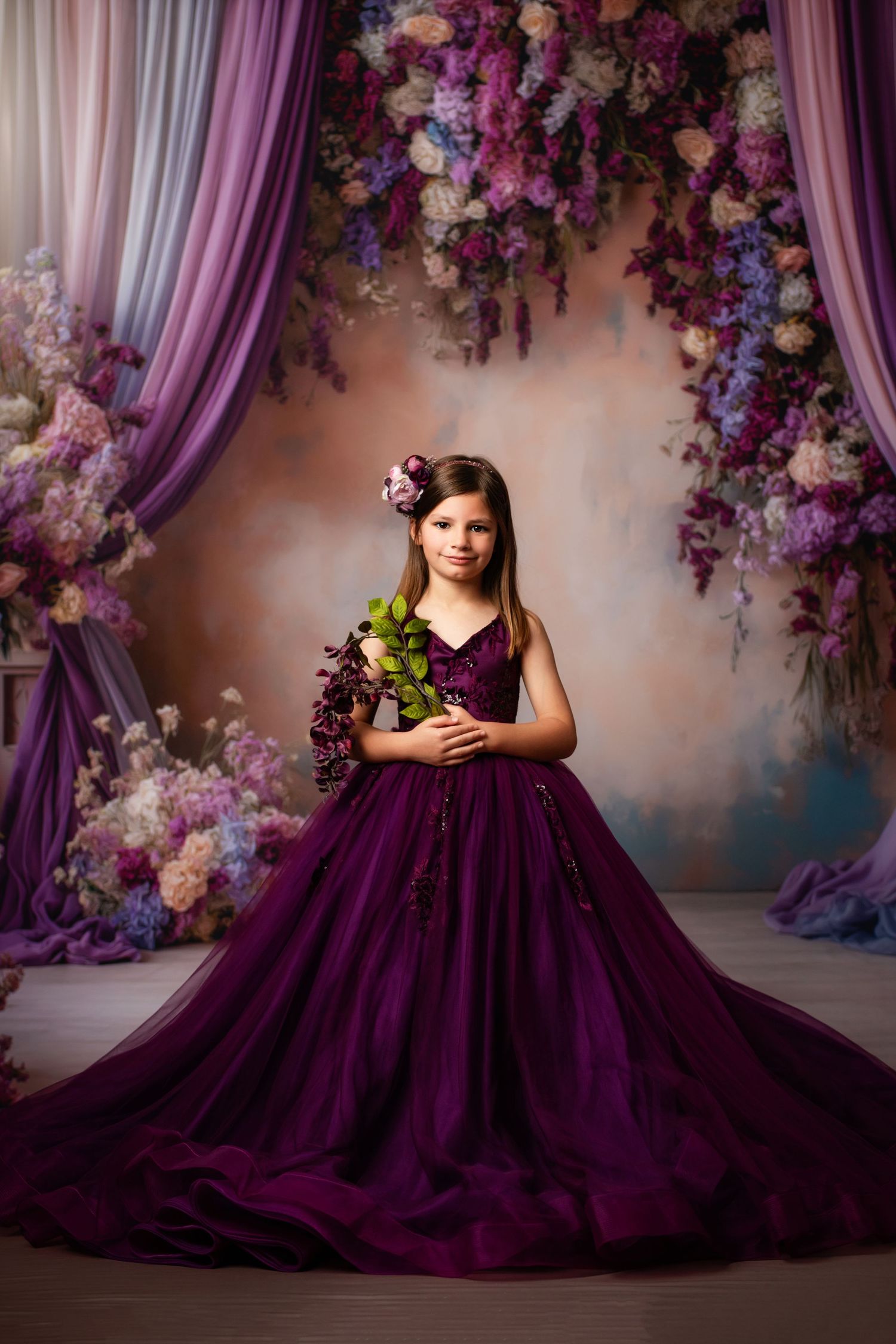A flowing purple ball gown with layers of tulle and a velvet bodice glows beautifully against a soft purple backdrop.