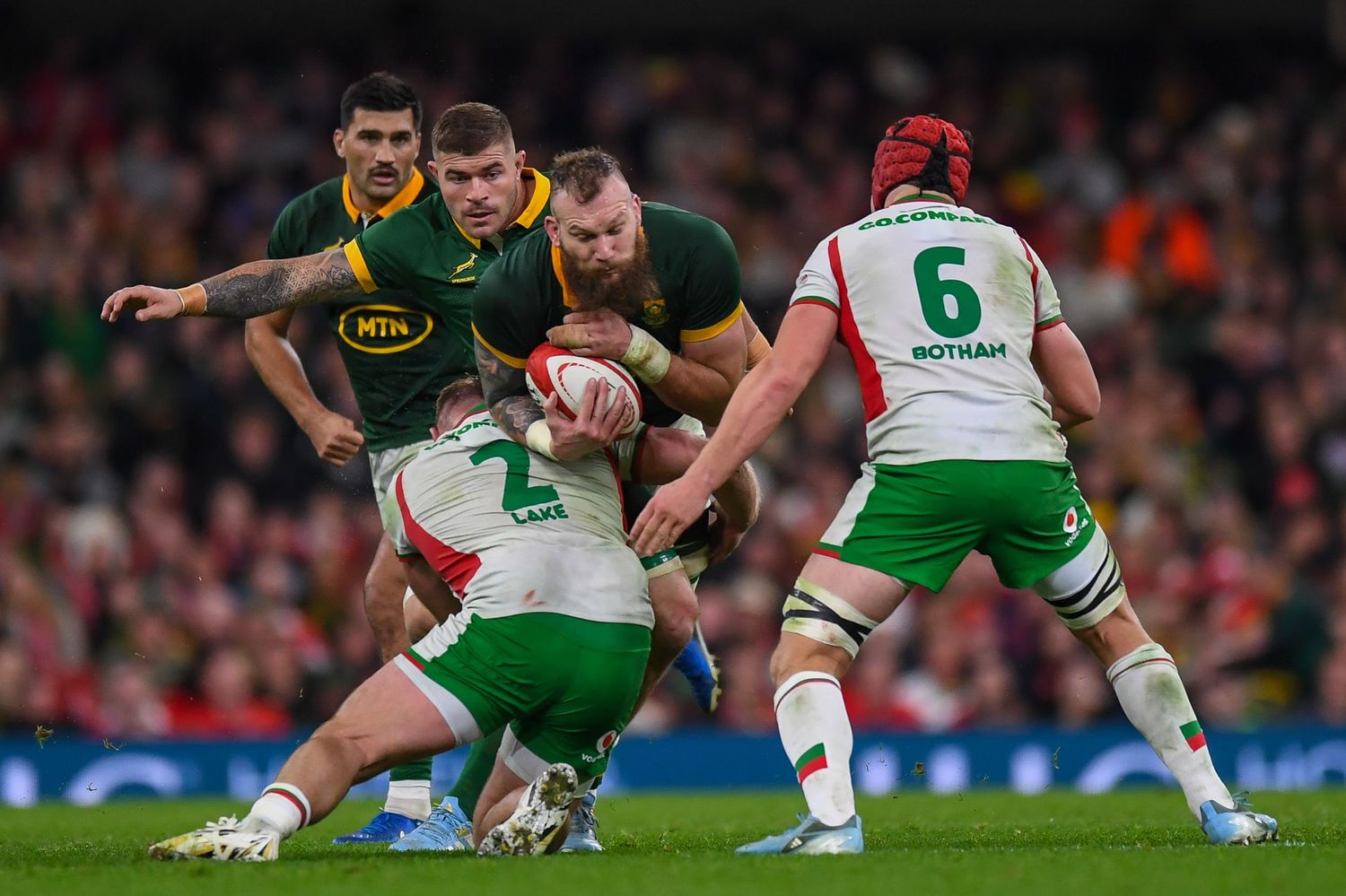 Rugby players from opposing teams clash in a physical tackle during an intense match at the stadium.