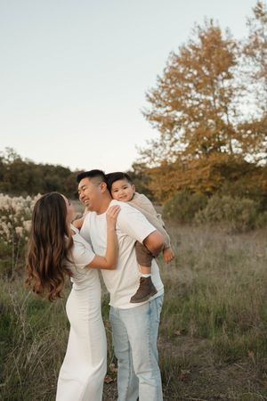 A loving family shares tender moments together in a field during golden hour.